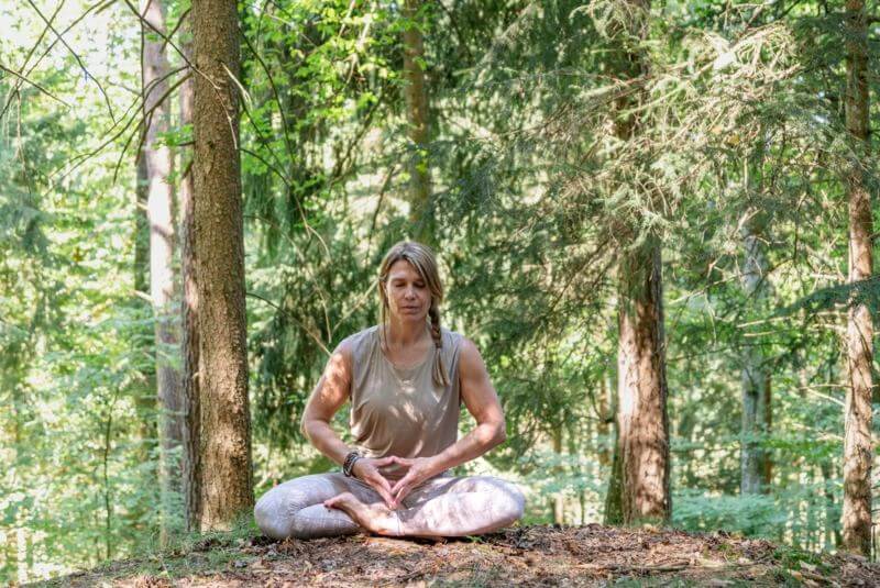 Frau meditiert im Wald.
