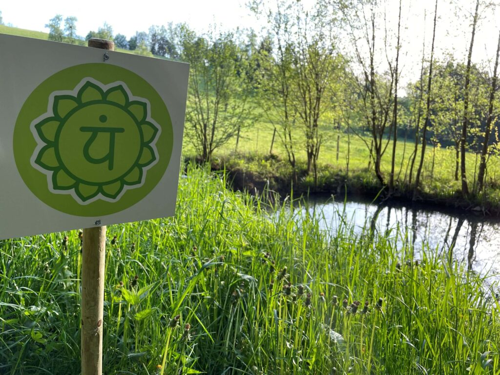 Schild am Wasser mit Chakra-Symbol