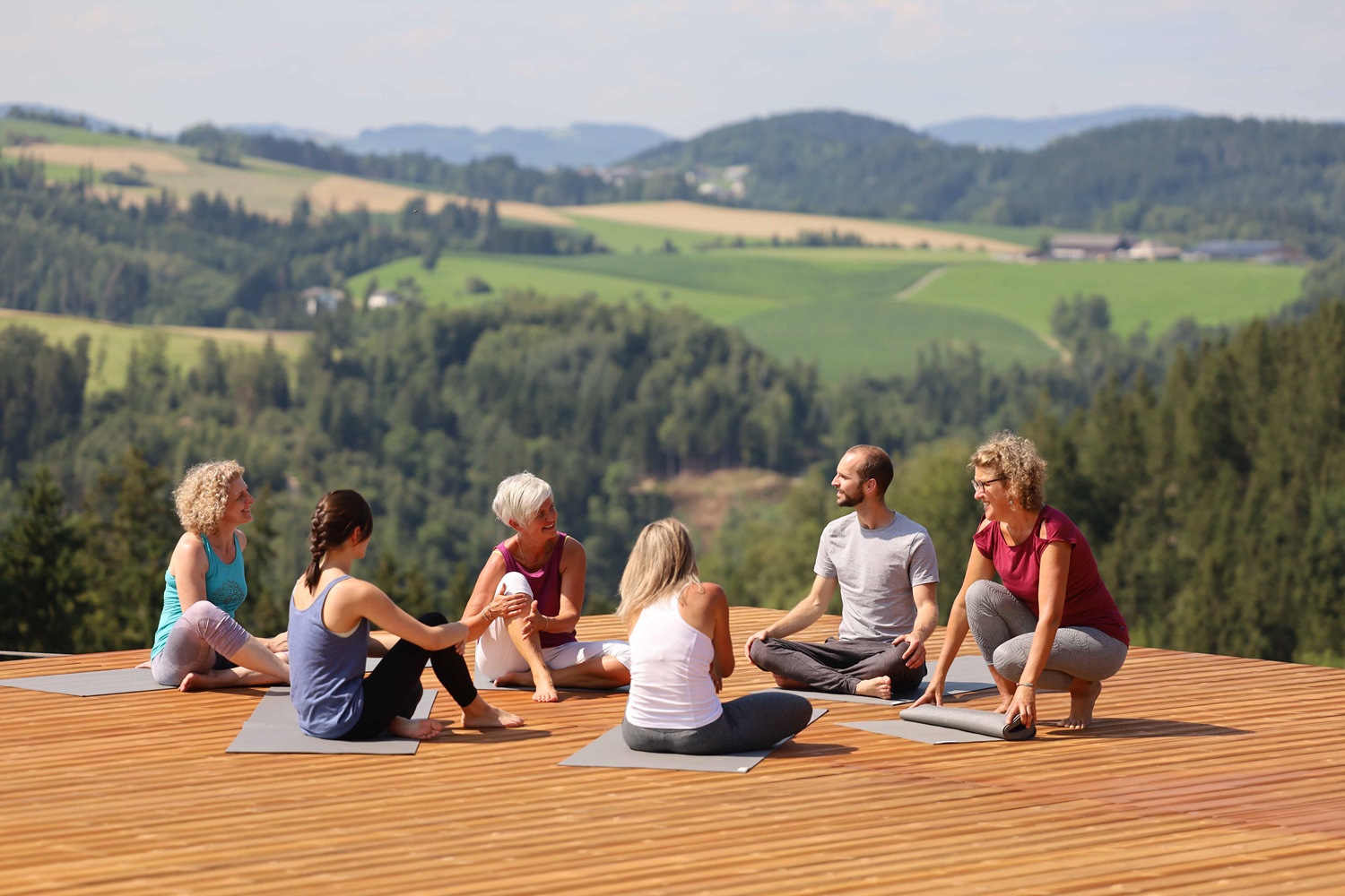 Yoga-Gruppe auf einer Holzplattform draußen
