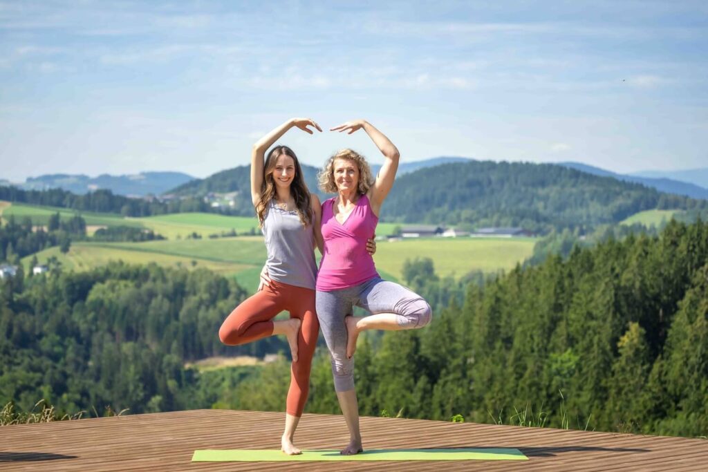 Zwei Frauen machen Yoga im Freien.