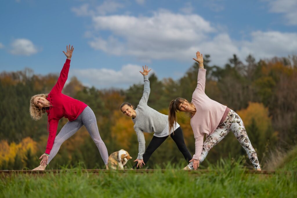 Drei Frauen machen Yoga im Freien.