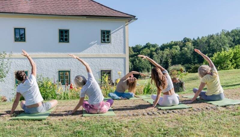 Fünf Frauen machen Yoga im Freien.