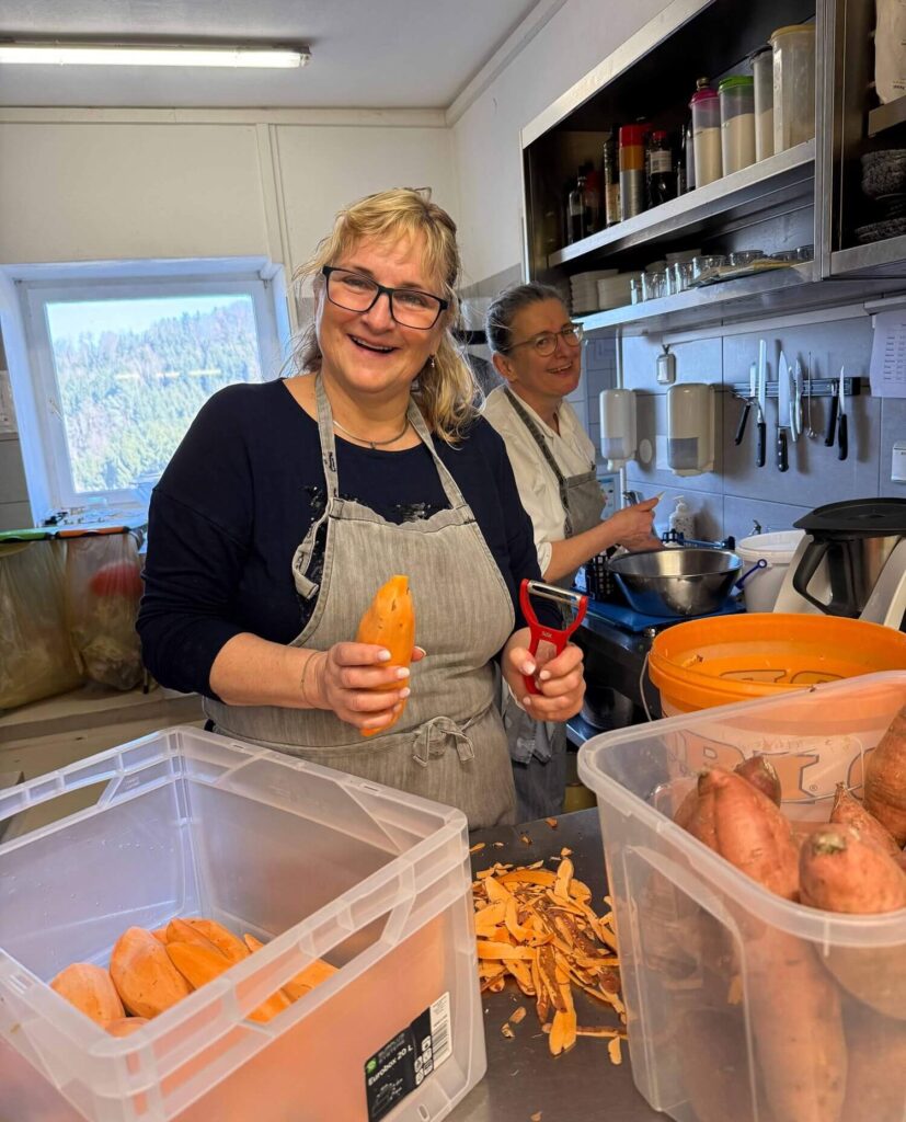 Frauen bereiten Süßkartoffeln in Küche vor.