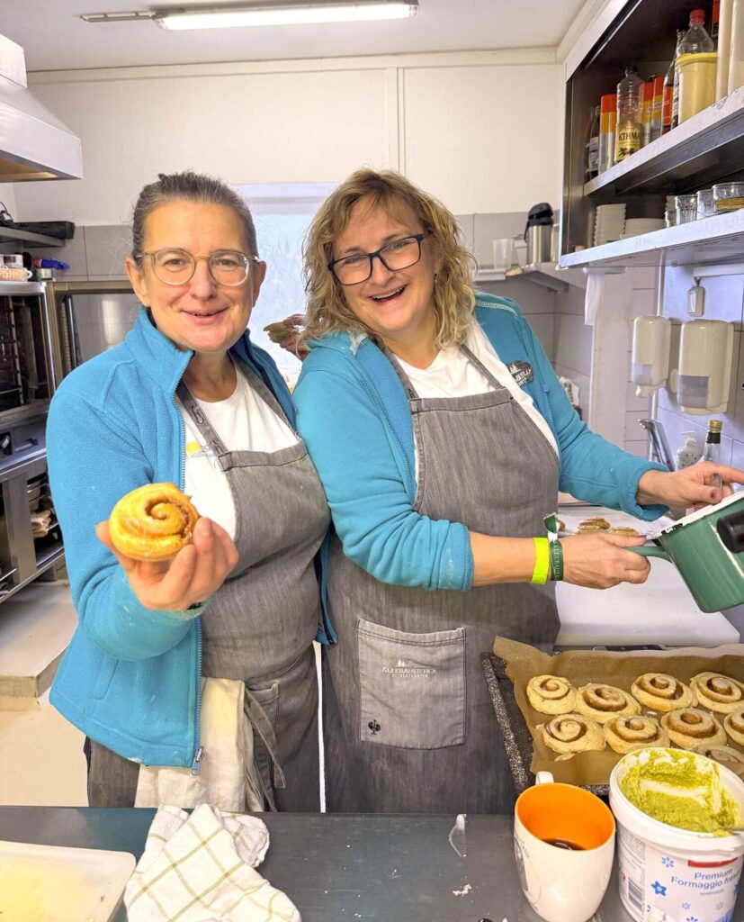 Zwei Frauen backen Zimtschnecken zusammen.