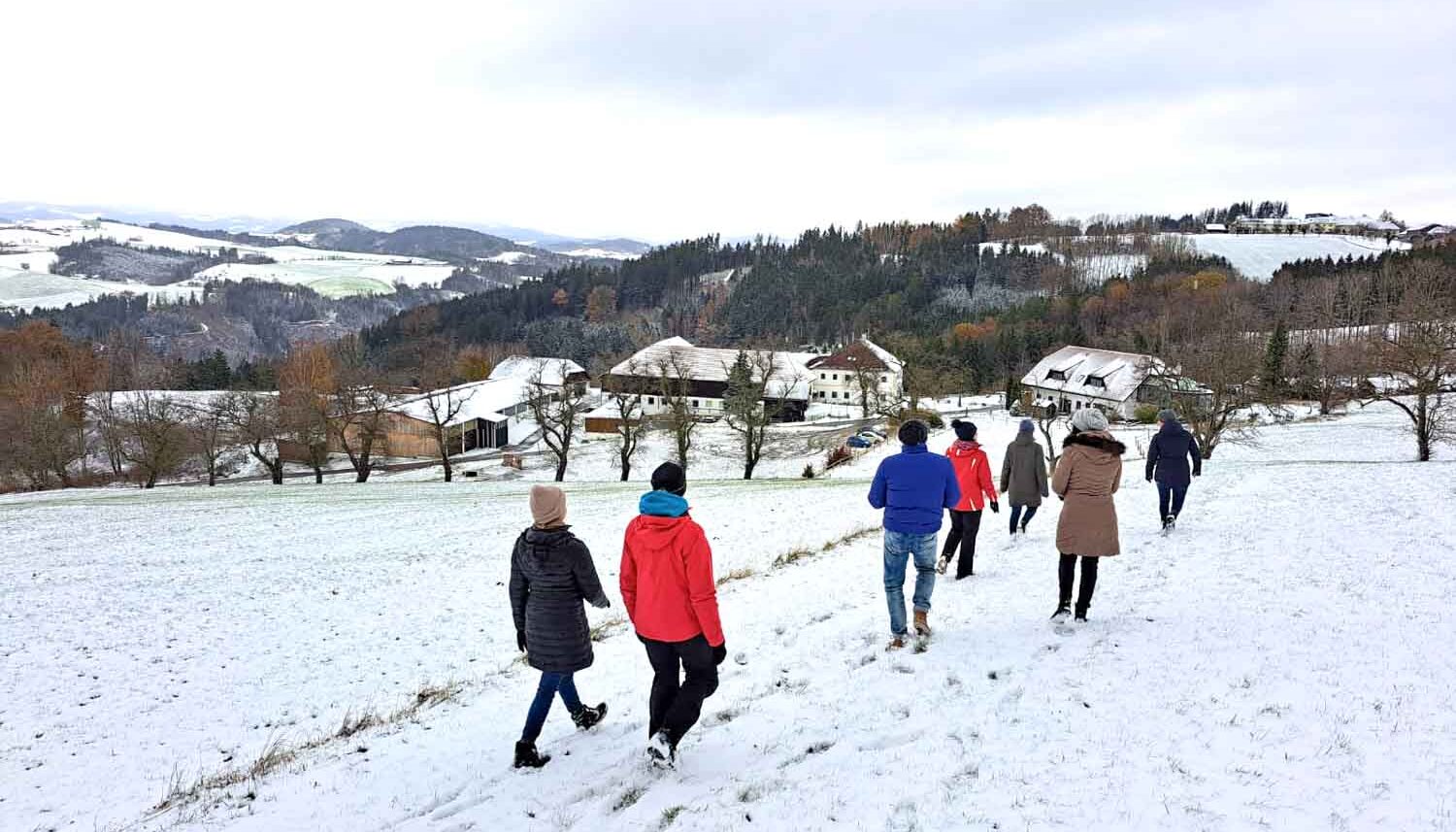 Menschen wandern durch verschneite Landschaft.