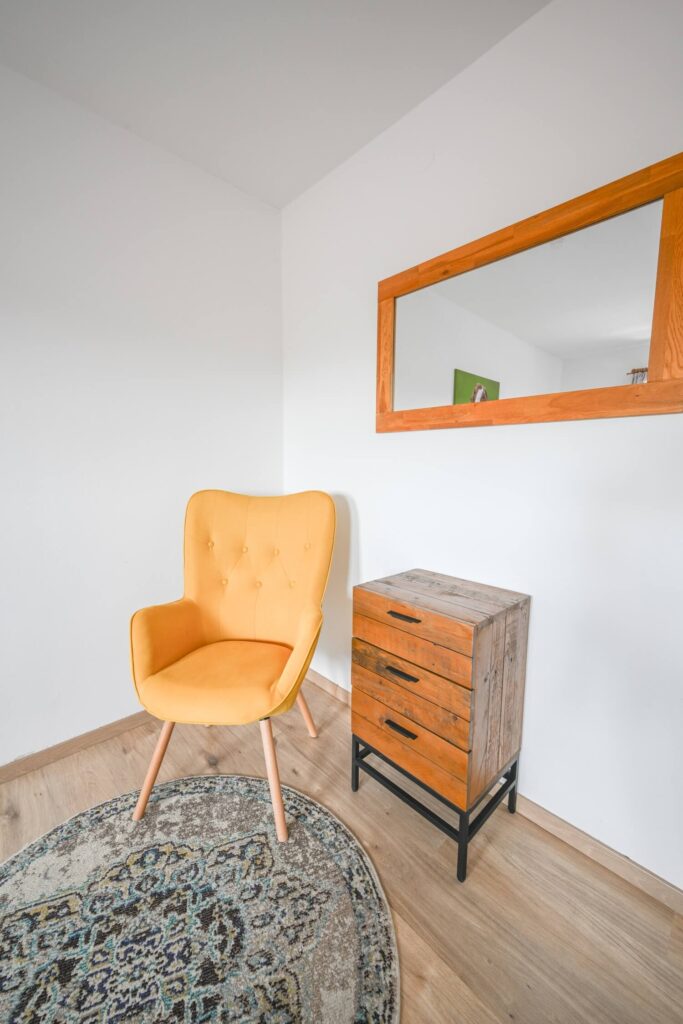 Gelber Stuhl, Holzkommode, Spiegel