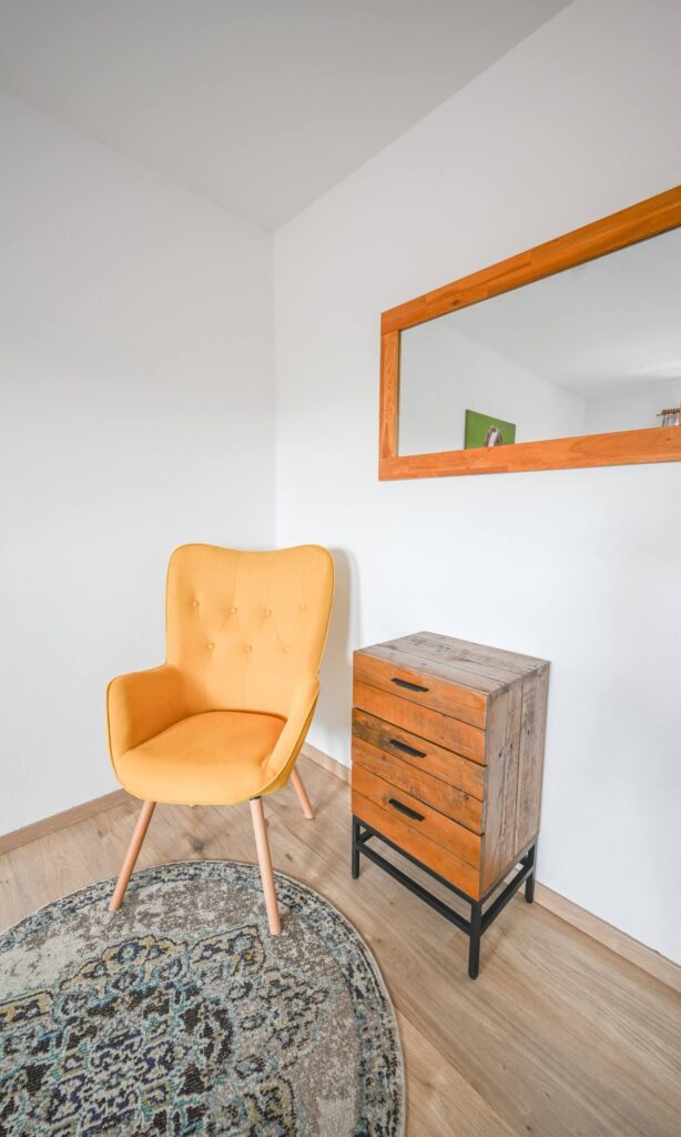 Gelber Stuhl, Holzkommode, Spiegel