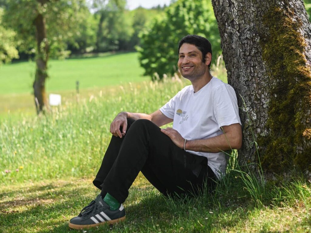 Mann sitzt unter einem Baum.