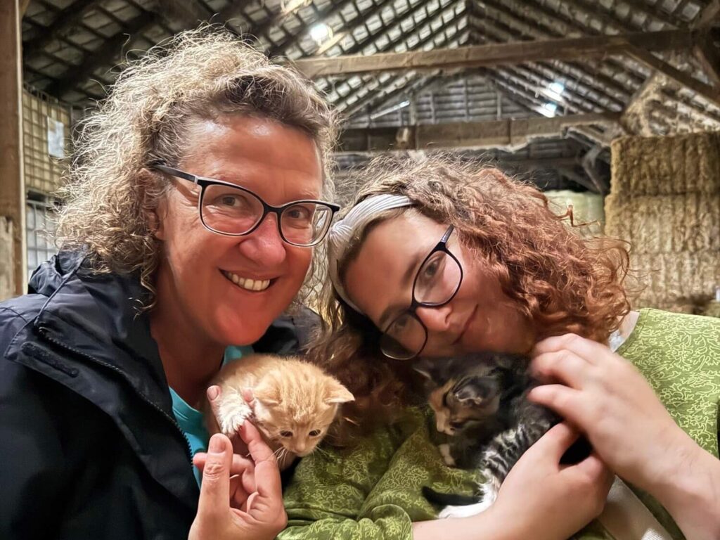 Zwei Frauen mit Kätzchen in Scheune