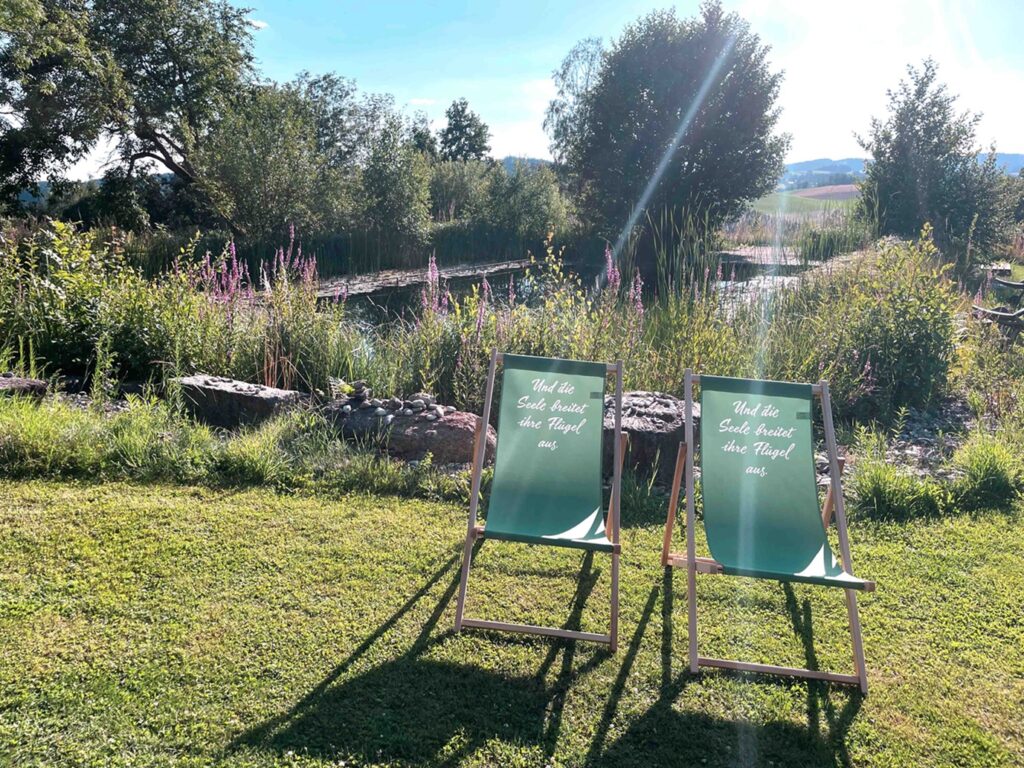 Zwei Liegestühle am Naturbadeteich.