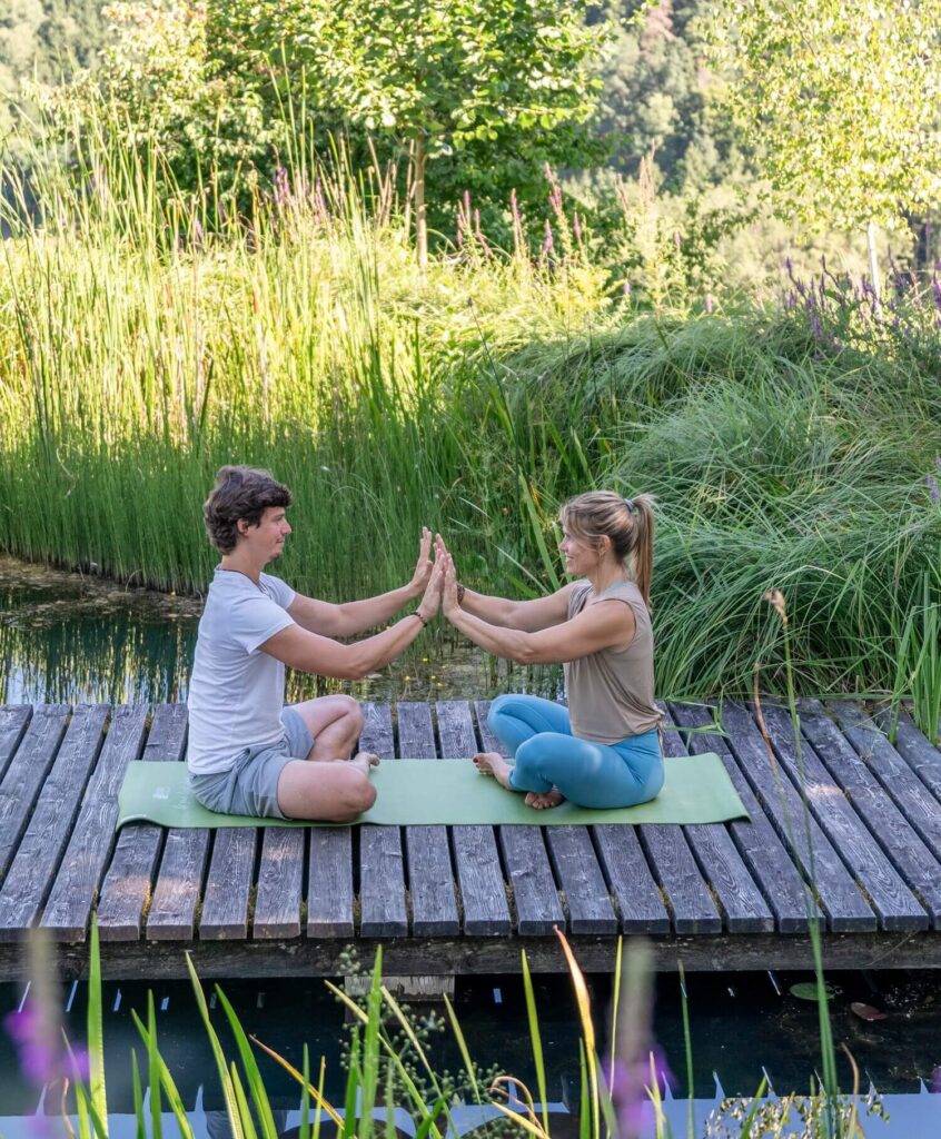 Zwei Personen meditieren am Steg.