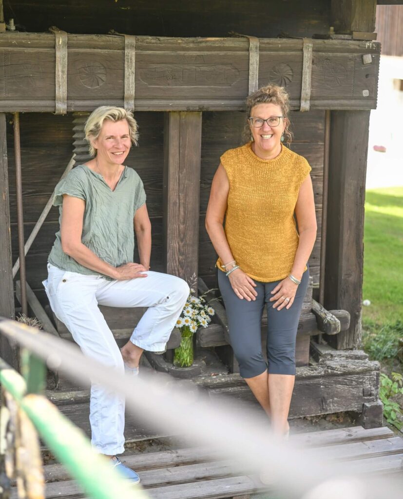 Zwei Frauen vor einem Holzgebäude
