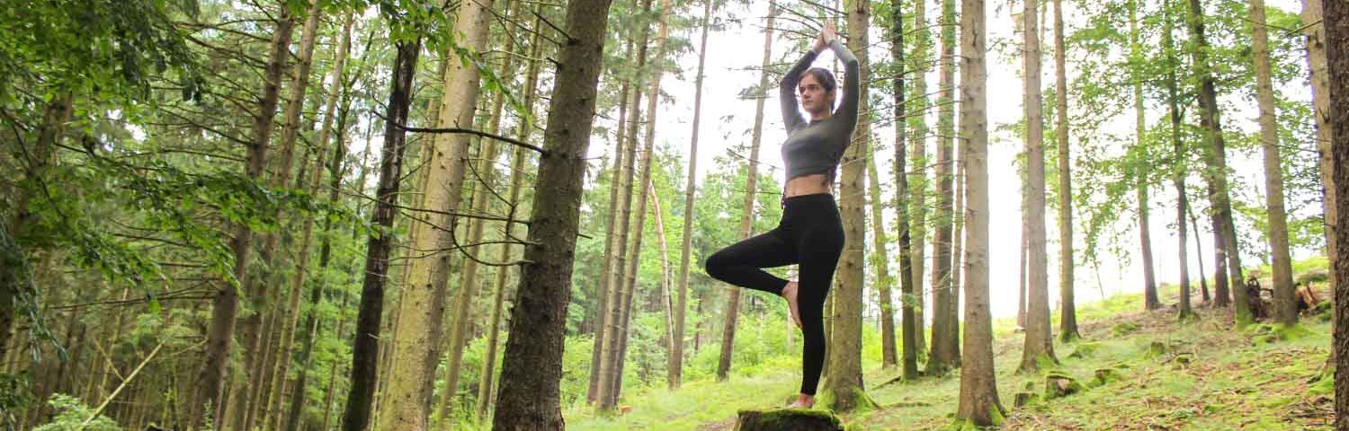 Frau macht Yoga im Wald.
