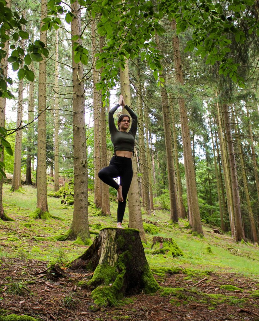 Frau macht Yoga auf Baumstumpf