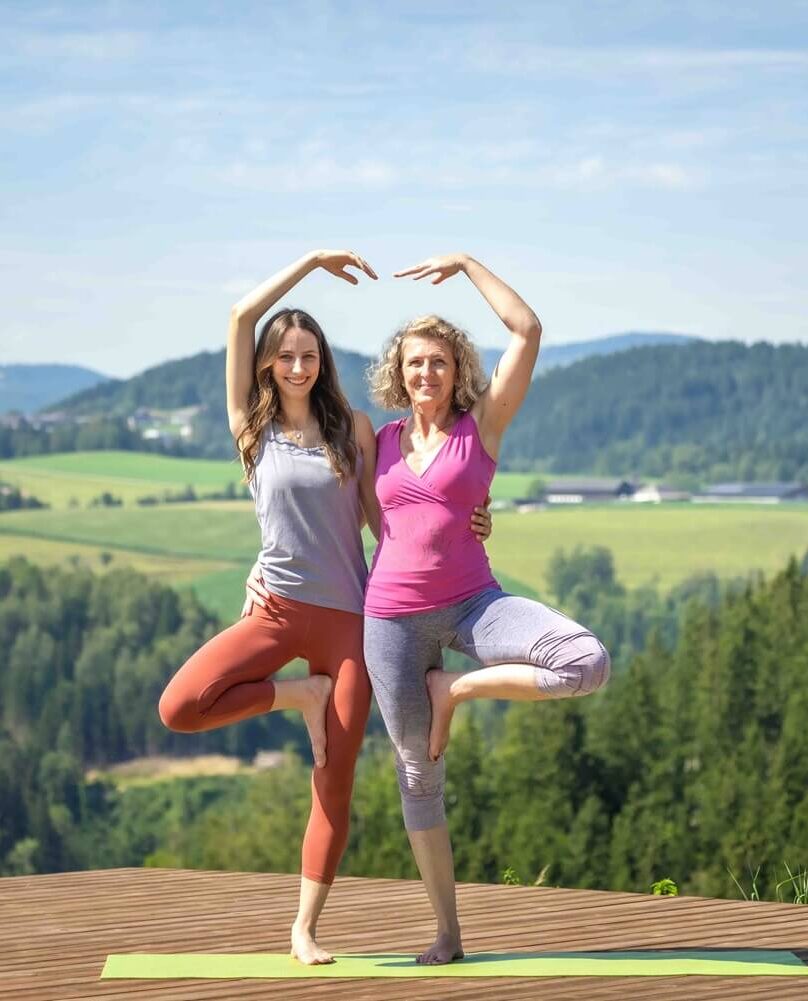Zwei Frauen machen Yoga im Freien.