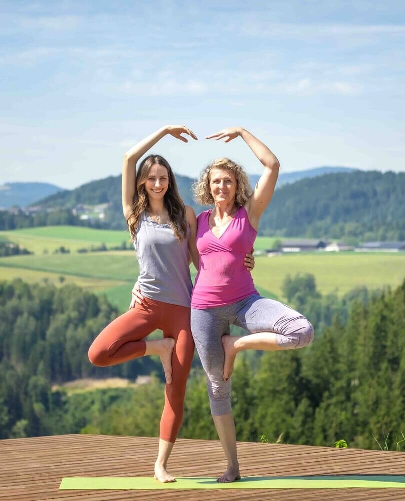 Zwei Frauen machen Yoga im Freien.